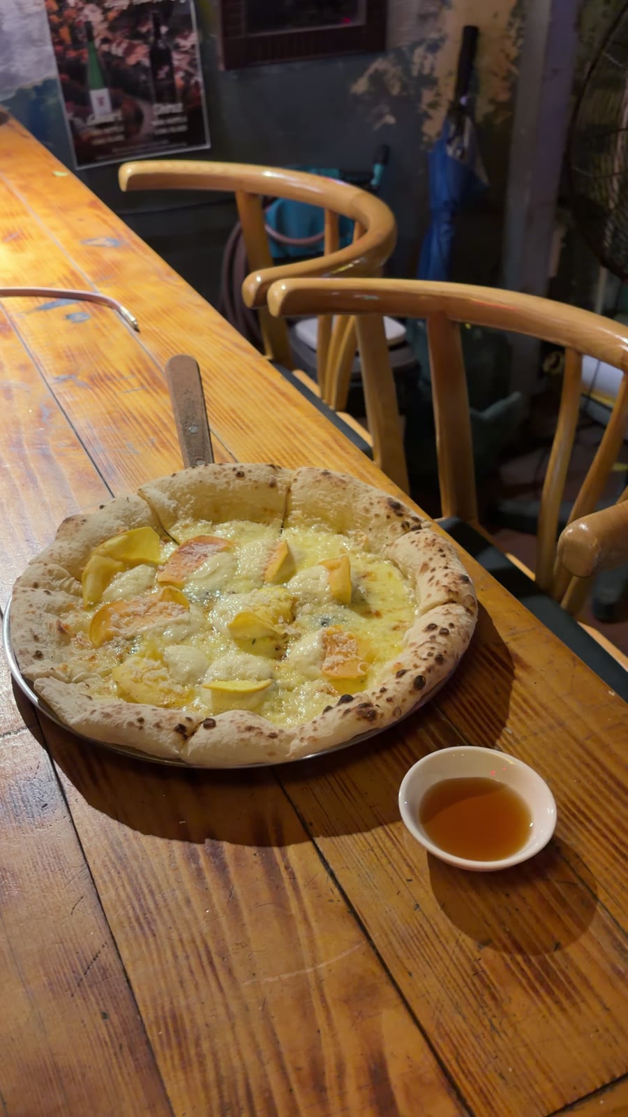 Chiếc pizza trên mặt bàn gỗ kèm chén sốt